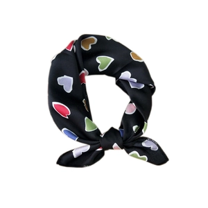 Elegant black silk scarf with colorful heart pattern tied in a stylish knot