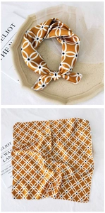 Detail of square silk scarf with yellow geometric pattern on a tray and flat layout