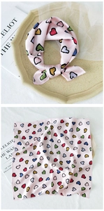 Detailed view of pink silk scarf with colorful heart patterns tied on a stone tray