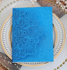 Detail of blue glitter laser-cut wedding invitation card on a decorative plate