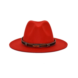 Close-up of red wide brim fedora hat featuring a bohemian beaded band and golden feather pin
