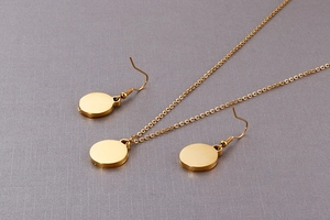 Detail of gold flower jewelry set featuring a circular pendant necklace and drop earrings
