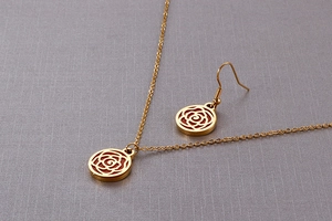 Detail of gold titanium jewelry set featuring intricate hollow rose flower patterns