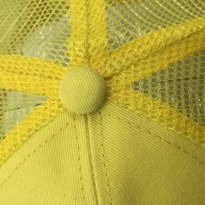 Détail macro de la casquette trucker jaune en maille avec bouton et coutures
