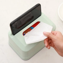 Multifunctional green tissue box with a built-in phone holder slot shown in use on a desk
