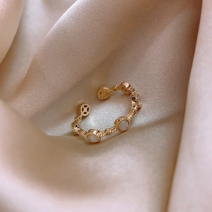 Detailed close-up of golden adjustable ring with white opal and small crystals on silk