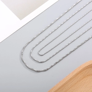 Polished silver stainless steel snake chain necklace displayed on a wooden stand
