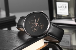 Gros plan de la montre YOLAKO avec cadran noir, aiguilles or rose et cuir