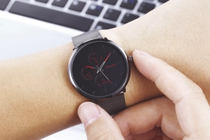 Close-up of Yolako chronograph watch with black mesh strap and red dial accents on wrist
