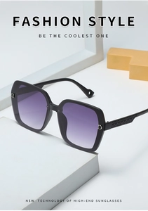 Detail of square black sunglasses with purple gradient lenses and gold D-logo on the temple