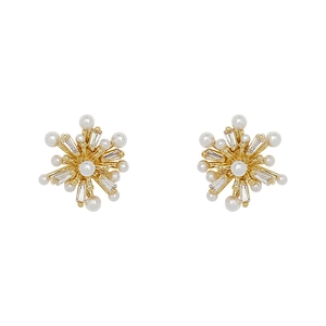 Exquisite gold snowflake earrings with sparkling zircons and white pearls on white background