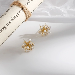 Elegant gold starburst earrings with sparkling zircon and pearls on textured background