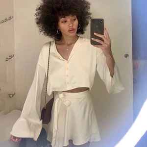 Selfie miroir montrant le haut en satin crème et la mini-jupe assortie avec lien à la taille