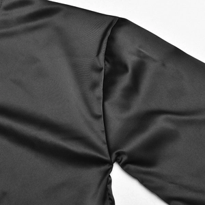 Gros plan sur la couture de l'épaule et la texture satinée lisse de l'ensemble noir