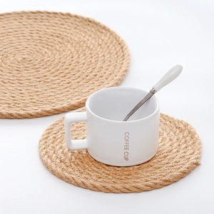 Detail of round woven linen placemats with a ceramic coffee cup on a clean white surface