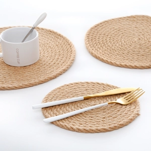 Close-up of round jute placemats with a white coffee mug and cutlery on white surface