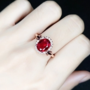 Elegant rose gold ring with ruby red oval gemstone and diamonds on model's hand