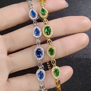 Elegant gold and silver link bracelets with emerald and sapphire teardrop gemstones