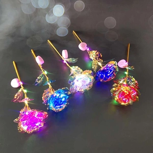 Detail of five glowing foil roses with LED lights and golden stems on dark background