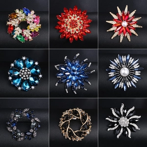Collection of crystal and pearl floral brooches in various alloy designs on black background