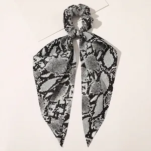 Detail of snake skin print hair scrunchie with long ribbons on a clean background