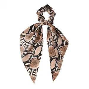 Detail of satin scrunchie with long bow featuring vintage snakeskin pattern texture