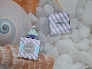 Detail of nautical baby shower gift boxes with blue stripes and sailboat decor