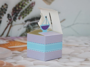 Close-up of blue nautical sailboat candy box with white stripes and paper material