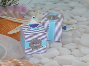 Blue and white striped nautical gift box with sailboat topper on seashell background