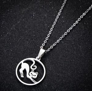 Macro shot of geometric hollow round cat pendant on a fine chain over black background