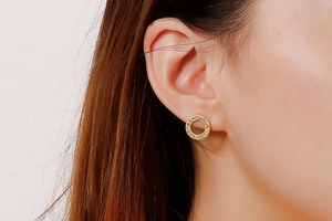 Close-up of rose gold hollow hoop earrings with pavé crystals on a female model