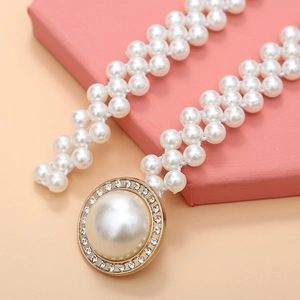 Detail of elegant double-strand pearl waist chain with rhinestone-encrusted gold buckle