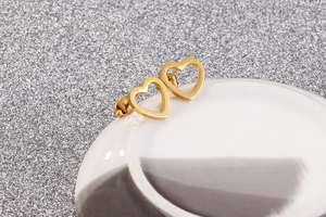 Detailed close-up of golden hollow heart earrings on a ceramic dish