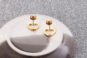 Detailed view of gold hollow heart studs on a white plate with metal butterfly backs