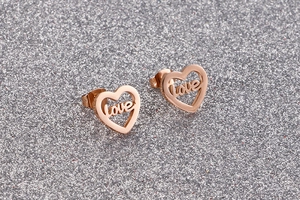 Macro view of rose gold heart-shaped love earrings on a sparkling silver background