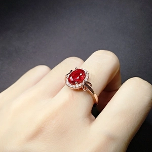 18k rose gold plated ring with oval ruby gemstone and halo diamonds worn on a finger