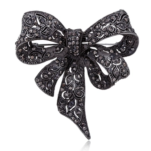 Elegant black bow brooch in dark metal with micro-pave stones on white background