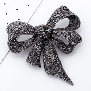 Vintage style bronze metal bow brooch with dark rhinestones and intricate floral carvings