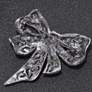 Vintage silver butterfly bow brooch with detailed pin back on dark glitter background