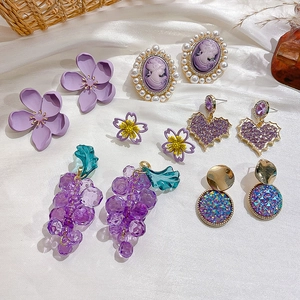 Chic purple earring set with floral, heart, and pearl designs on white silk fabric