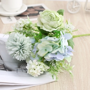 Artificial bouquet with light green and blue roses, hydrangeas, and mums on a wooden table