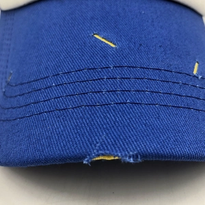 Close-up of distressed blue baseball cap brim with yellow contrast fabric and stitching