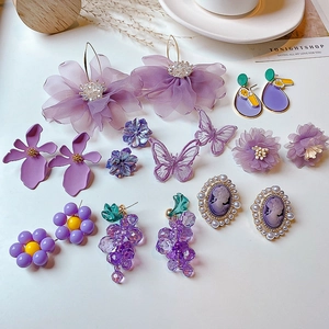 Detailed flat lay of purple fashion earrings featuring fabric flowers and resin butterflies