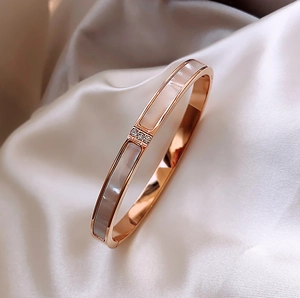 Detailed shot of rose gold stainless steel bangle with white shell inlay on satin