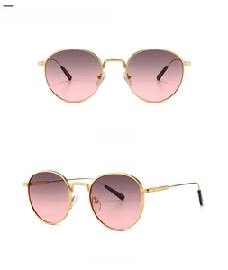 Detail of round metal sunglasses with gold frames and gradient grey pink lenses