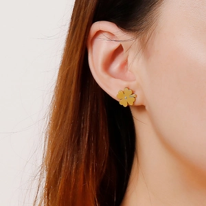 Elegant gold four-leaf clover stud earrings worn by a model in a close-up shot