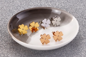 Close-up of four-leaf clover earrings in gold, silver, and rose gold with zircon
