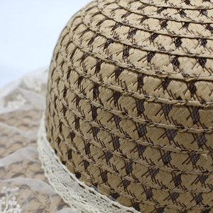 Close-up of the sun hat showing intricate straw weave and delicate white lace trim
