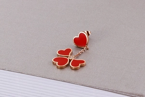Detailed close-up of rose gold earrings with red heart enamel and sparkling zircon