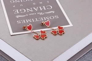 Macro shot of rose gold heart clover earrings with red enamel on a stylish card